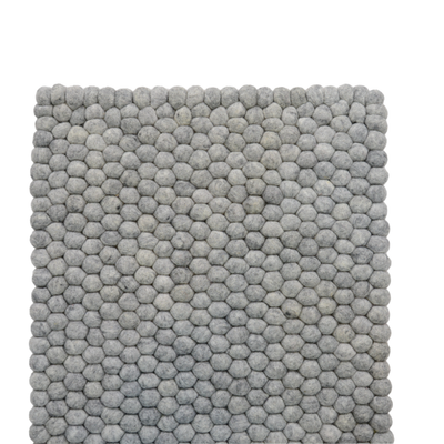 Tappeto per cameretta in feltro grigio fatto a mano con palline di lana.
