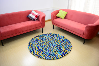 Tapis rond artisanal en feutre de laine à boules bleu et jaune